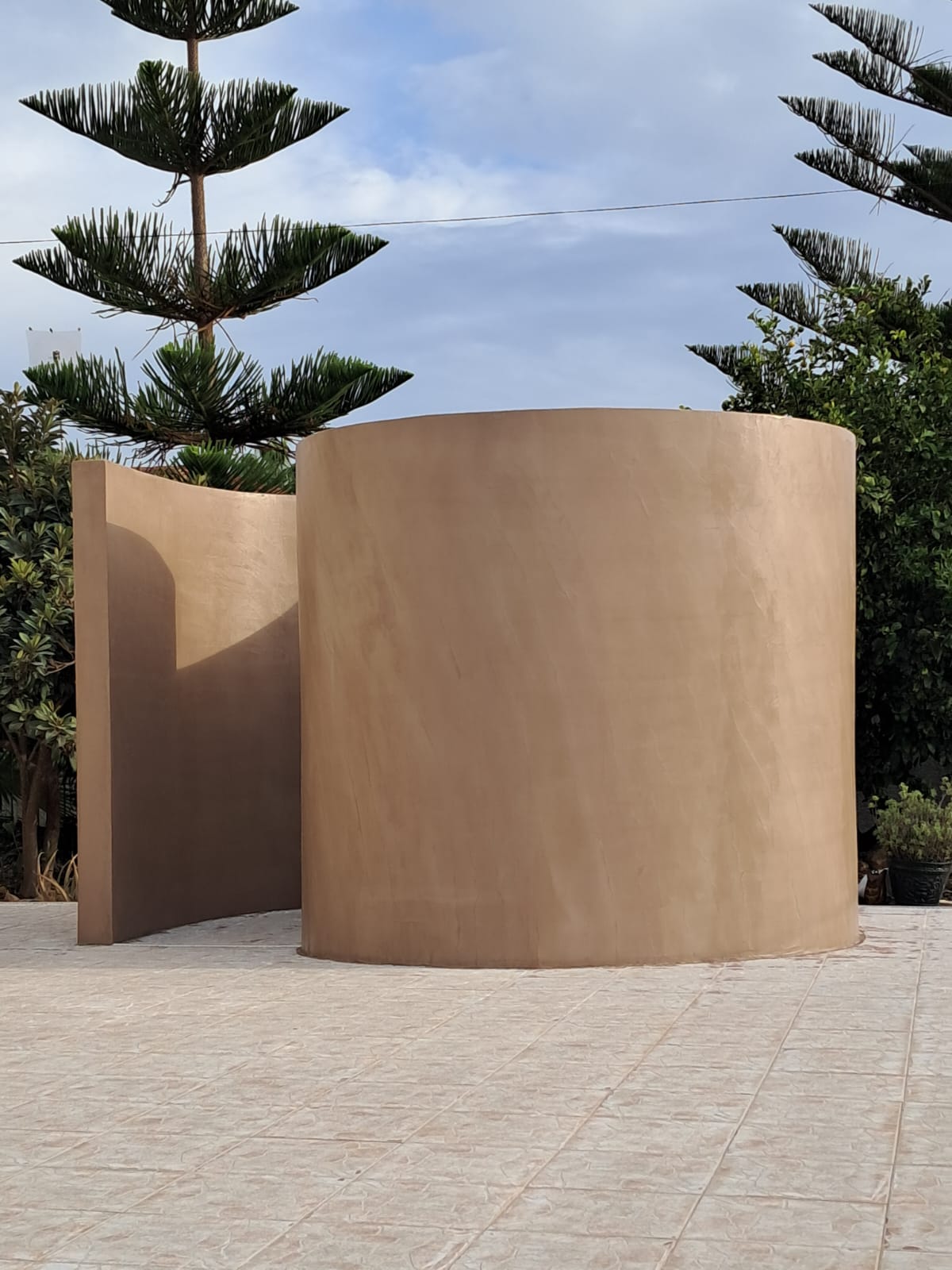 Vue d'ensemble d'une douche extérieure courbe en béton ciré réalisée sur mesure par ZTR